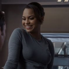 a woman standing next to a man in a gray shirt and smiling at each other