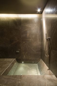 a bathroom with marble walls and flooring, shower head and hand held showerhead