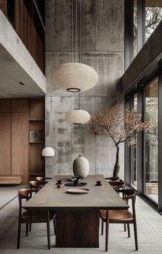 a dining room table with chairs and vases on top of it in front of large windows