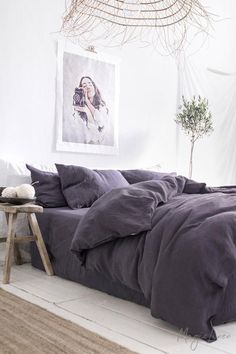 a large bed sitting in a bedroom next to a wooden table with a plant on it