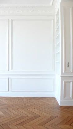 an empty room with white walls and parquet flooring in the center is shown