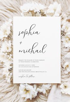 the wedding stationery is surrounded by white flowers