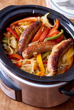 sausages and peppers are cooked in the crockpot on the wooden table top