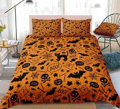 a bed with an orange and black halloween themed comforter on it's side