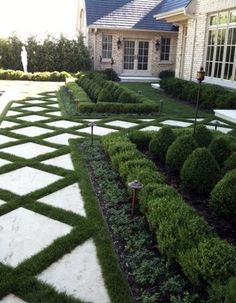 a large yard with hedges and stone walkways