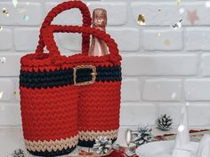 a knitted red purse sitting on top of a white table next to christmas decorations