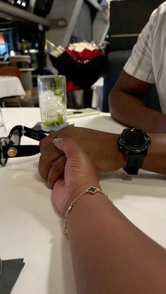 two people sitting at a table holding hands