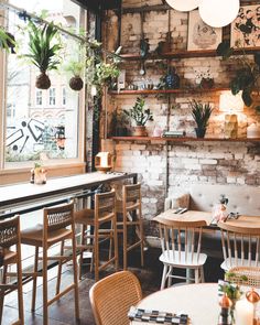 the interior of a restaurant with tables, chairs and potted plants on the wall