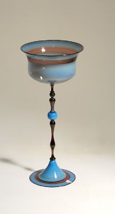 a blue glass is sitting on a white surface with a brown stripe around the edge