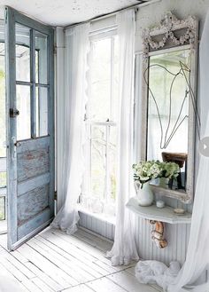 a room with a table, mirror and vase on the window sill in it