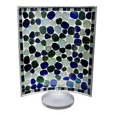 a blue and green mosaic tile dish on a white plate with a silver stand in front of it