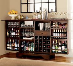 a bar with lots of bottles and glasses on top of it next to a mirror