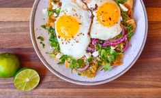 two fried eggs sit on top of a bed of lettuce and red onions