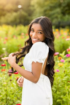 a beautiful young woman standing in a field of flowers