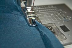 the sewing machine is stitching through the fabric on the blue material that has been sewn