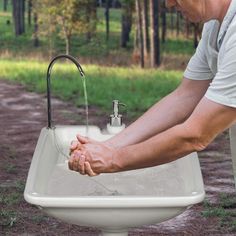 a man is washing his hands in a white sink with water running from the faucet