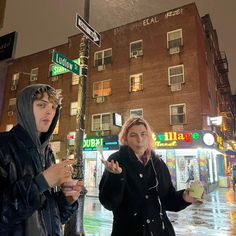 two people standing in the rain on a street corner