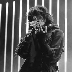 black and white photograph of a person holding a microphone in front of a striped wall