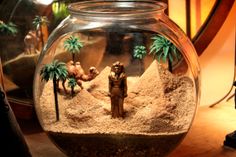 a glass bowl filled with sand and palm trees