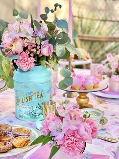 a table topped with pink flowers next to a blue jar filled with powdered sugar