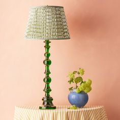 a green lamp sitting on top of a table next to a blue vase