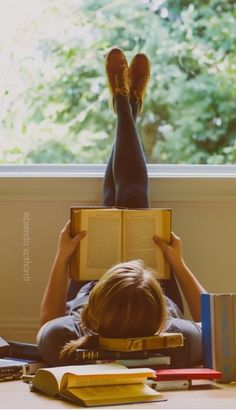 a person laying on the floor reading a book with their feet up in front of them