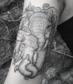 an elephant with flowers on its head is shown in black and white tattoo art work