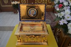 a gold and blue box sitting on top of a yellow table next to white flowers