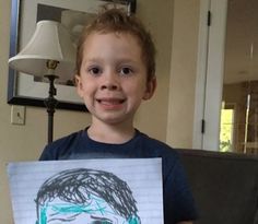 a young boy holding up a drawing of himself