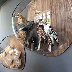 several stuffed animals are placed in a glass bowl on the wall next to wooden letters