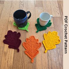 four crocheted leaf coasters sitting on top of a wooden floor next to a coffee cup