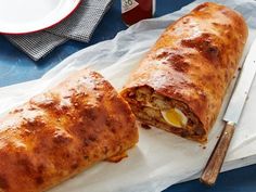 two burritos cut in half sitting on top of a white napkin next to a knife and fork