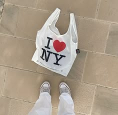 a white bag with i love new york printed on it next to someone's feet