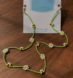 the necklace is made with green string and white flowers on each side, along with yellow beads