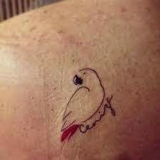 a small bird tattoo on the back of a woman's shoulder