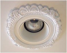 a white ceiling light with an ornate design on the top and bottom part, mounted in a wall or ceiling