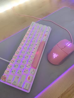 a pink computer mouse and keyboard on a gray surface with purple light coming from behind it