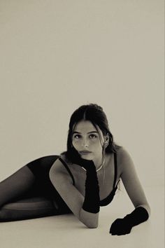 a woman is laying on the floor with her hand under her chin and wearing black gloves