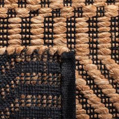 an area rug with braided edges and black, brown and tan colors on it