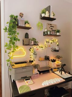 a desk with some plants on it and a printer in front of the computer screen