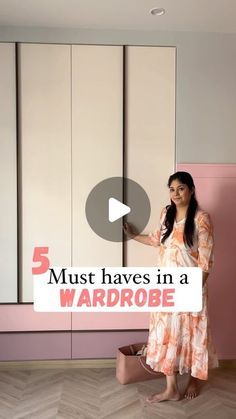 a woman standing in front of a pink wall holding a sign that says 5 must haves in a wardrobe