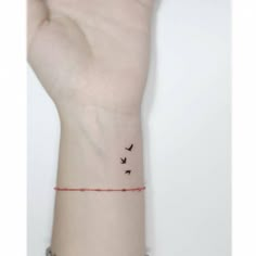 a person's wrist with two birds on it and a red string attached to the wrist