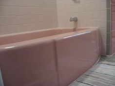 a pink bath tub sitting next to a walk in shower