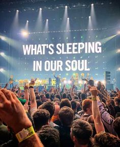 a large group of people at a concert with their hands up in the air, and an advertisement that says what's sleeping in our soul