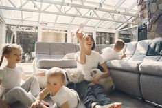 a woman sitting on the floor with two children and a dog in front of her