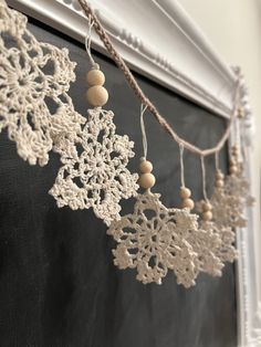 snowflakes are hung on a chalkboard with string