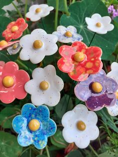 colorful ceramic flowers are displayed in the garden