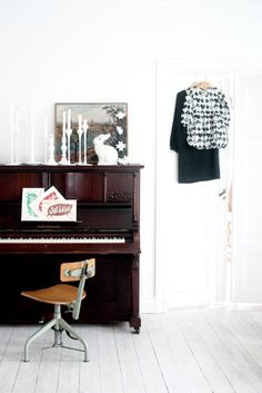 an old piano is in the corner of a room with white walls and wooden floors