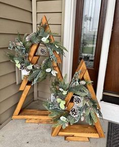 two wooden christmas trees with pine cones and greenery on them sitting in front of a house