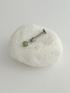 a pair of earrings sitting on top of a white rock next to a green bead